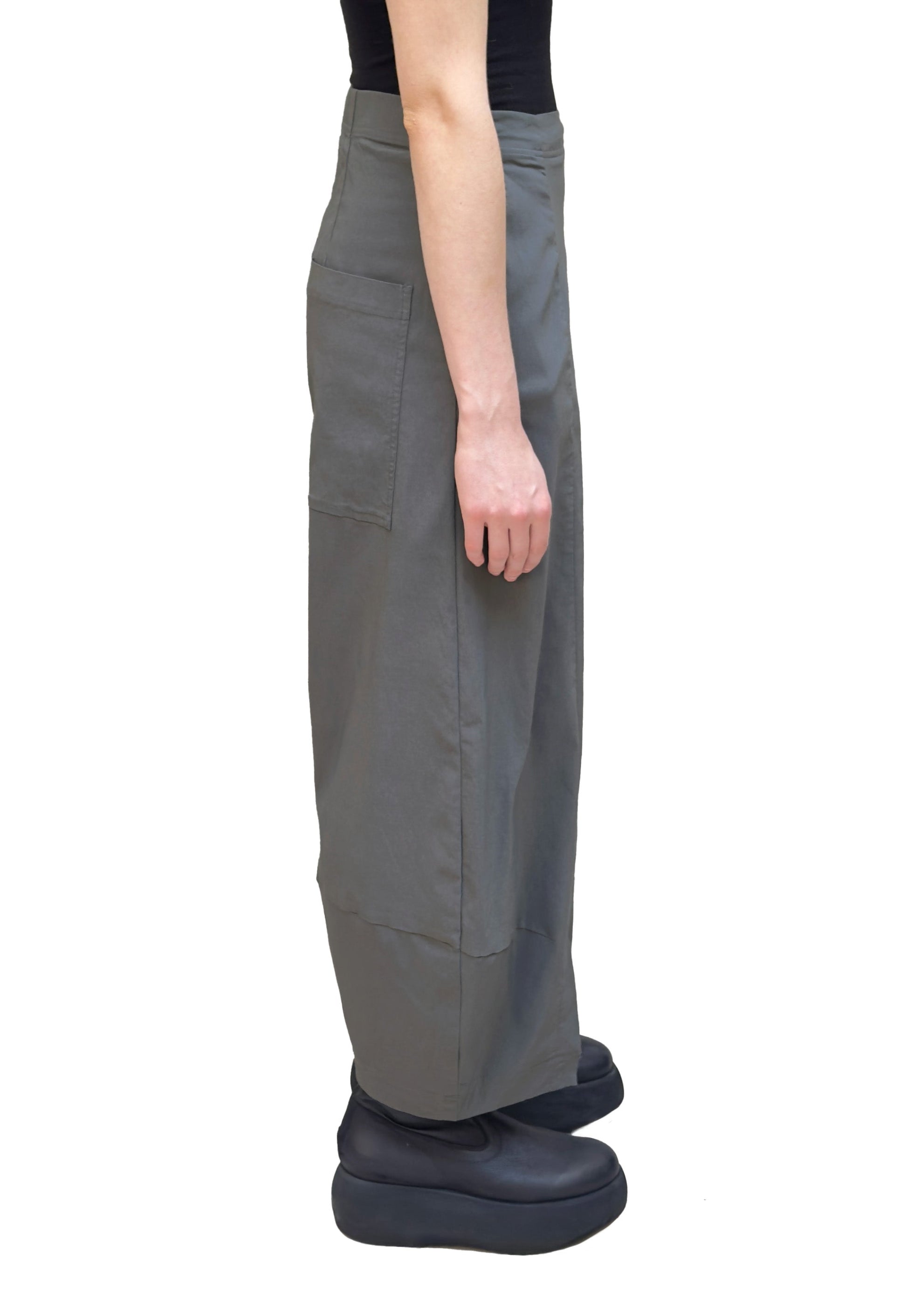 Women's long barrel leg pant with flat elastic waistband, side pockets, back patch pockets and asymmetric hem. Made in a technical stretch fabric from Black Label. In colour dark grey. Side view. 