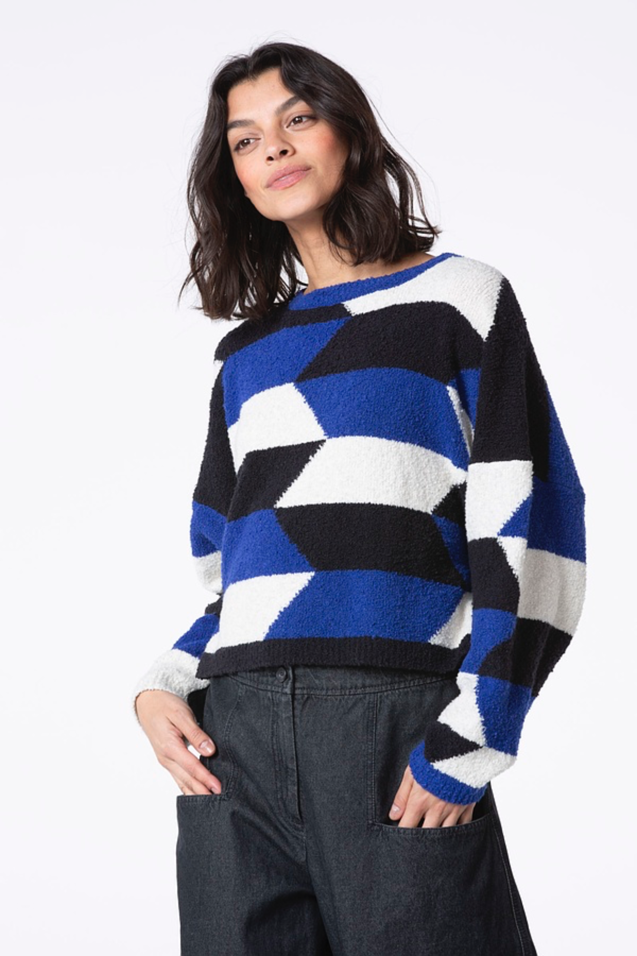 Women's cropped long sleeve pullover made from a boucle yarn knit from Oska. In geometric blue, black, and white pattern. Front view.