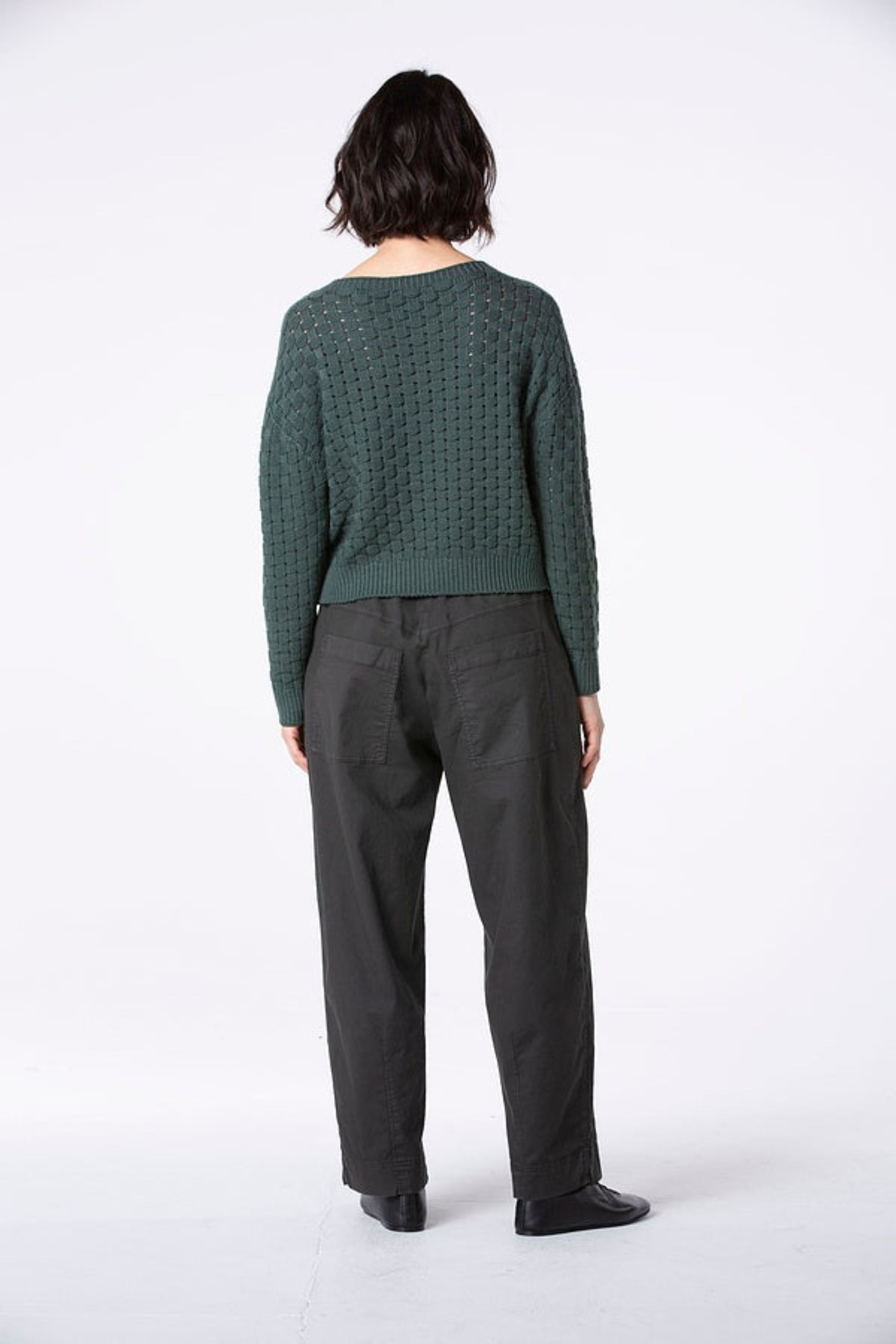 Women's long barrel leg pant with flat front button closure, curved front slash pockets and back patch pockets. Made in a textured cotton fabric from Oska. Back view.