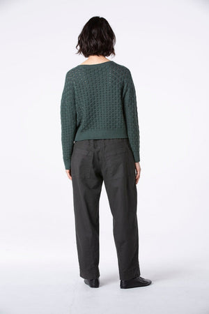Women's long barrel leg pant with flat front button closure, curved front slash pockets and back patch pockets. Made in a textured cotton fabric from Oska. Back view.