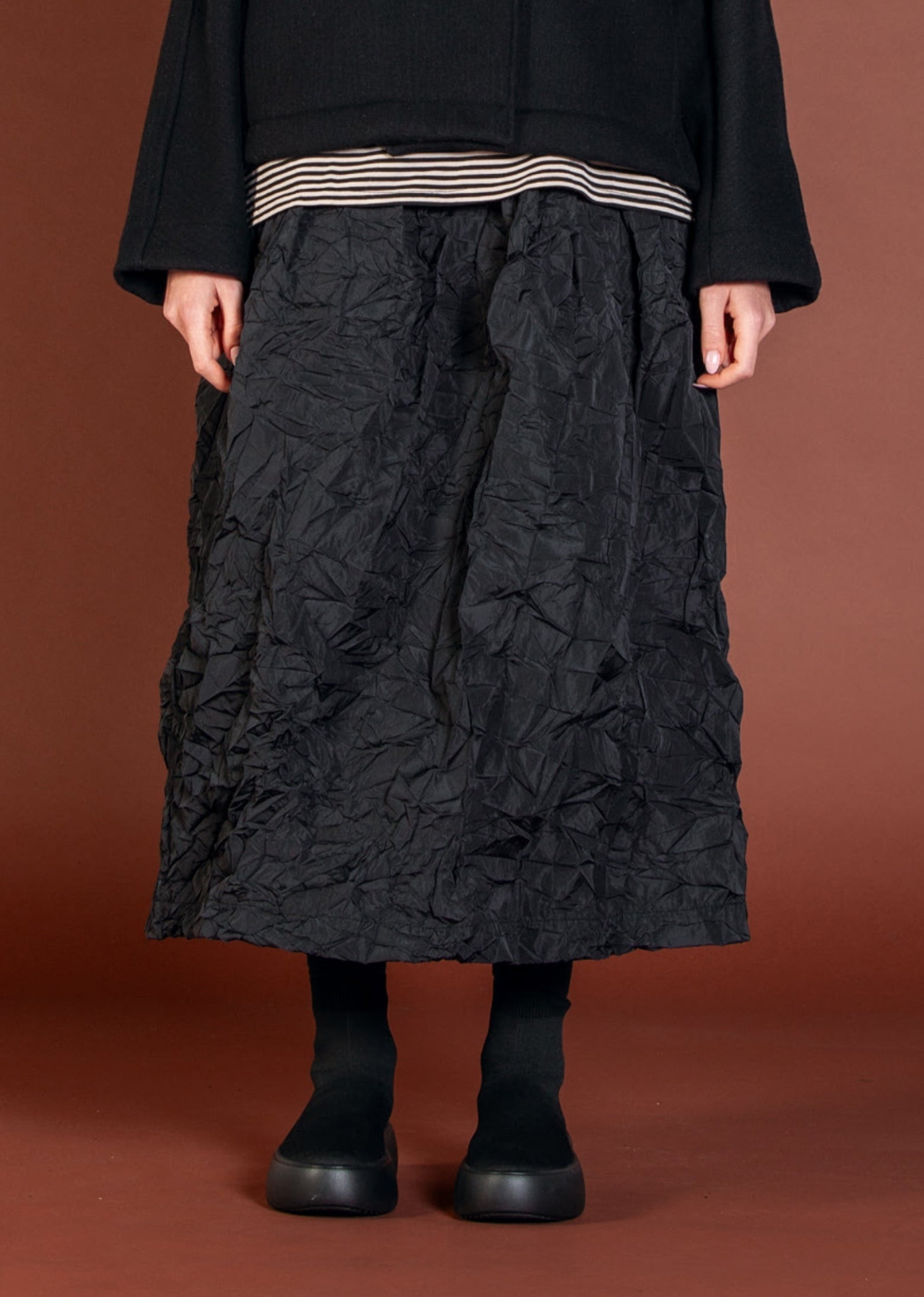 Women's long A-line pocketed skirt with elasticized waist band froM Mama B. Made in a crinkle fabric. In colour black. Front view.