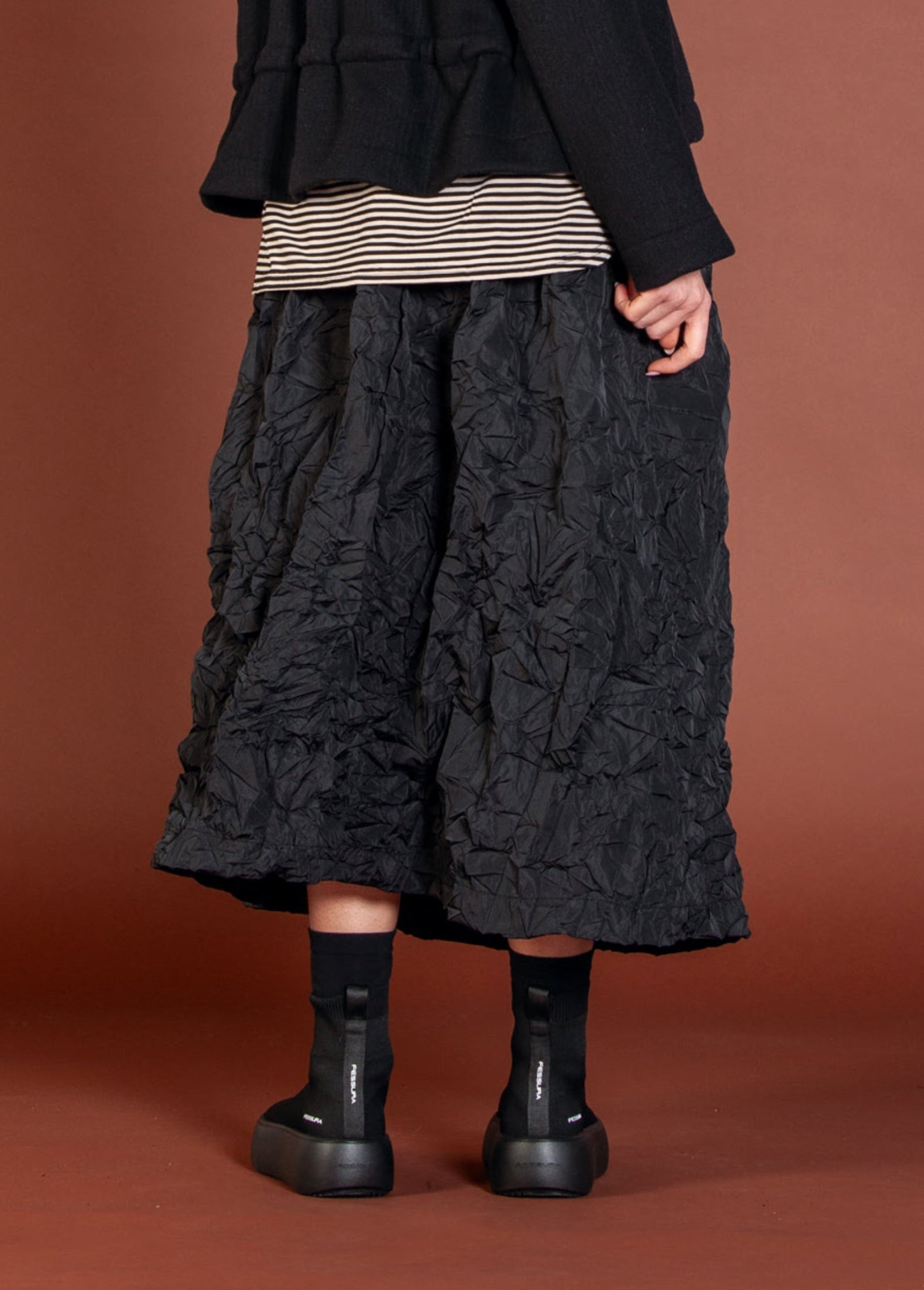 Women's long A-line pocketed skirt with elasticized waist band froM Mama B. Made in a crinkle fabric. In colour black. Back view.