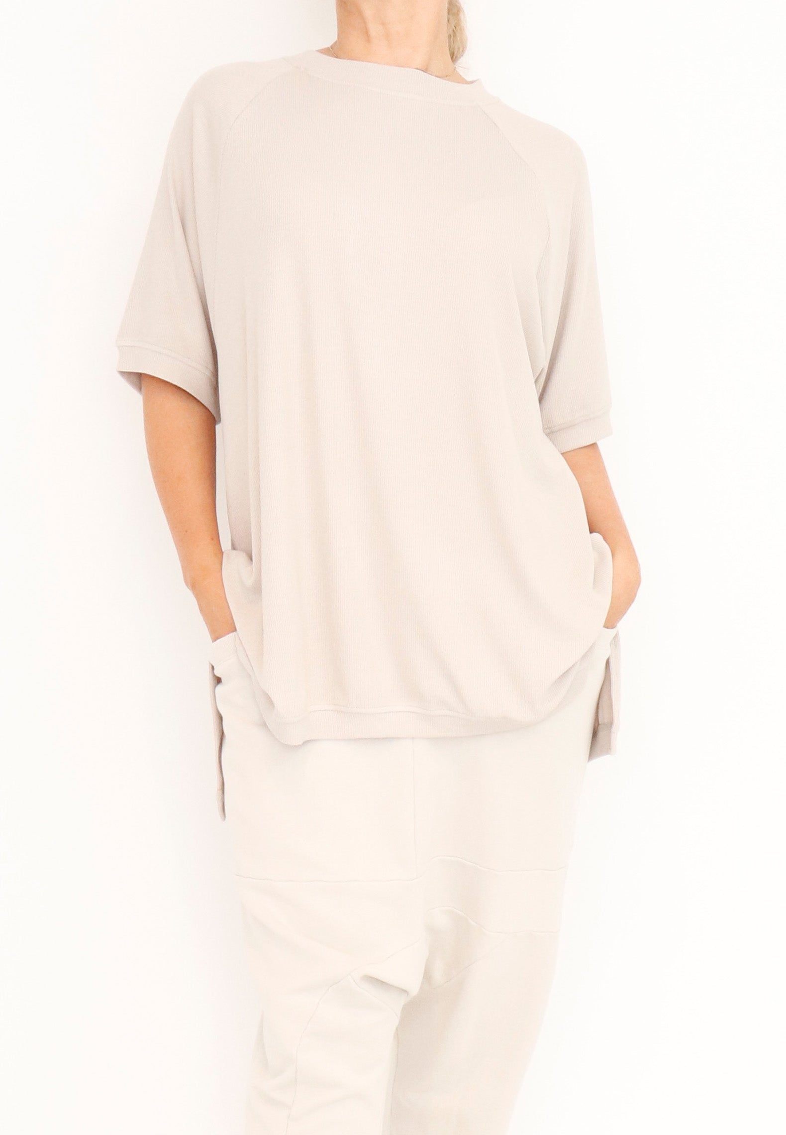 Women’s short Ragland sleeve top, in a ribbed viscose knit fabric from Sort Aarhus.Features a hi-Low cut with 7” slits on the sides. In colour crème. Full view.