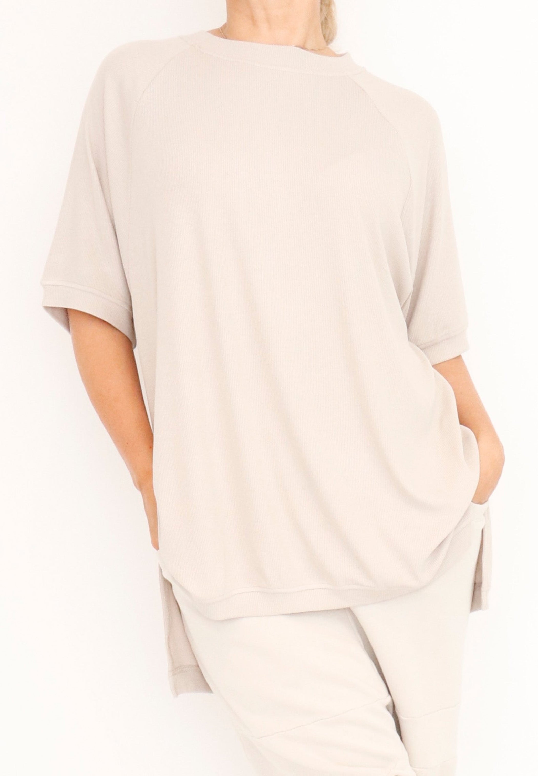 Women’s short Ragland sleeve top, in a ribbed viscose knit fabric from Sort Aarhus.Features a hi-Low cut with 7” slits on the sides. In colour crème. Front view.