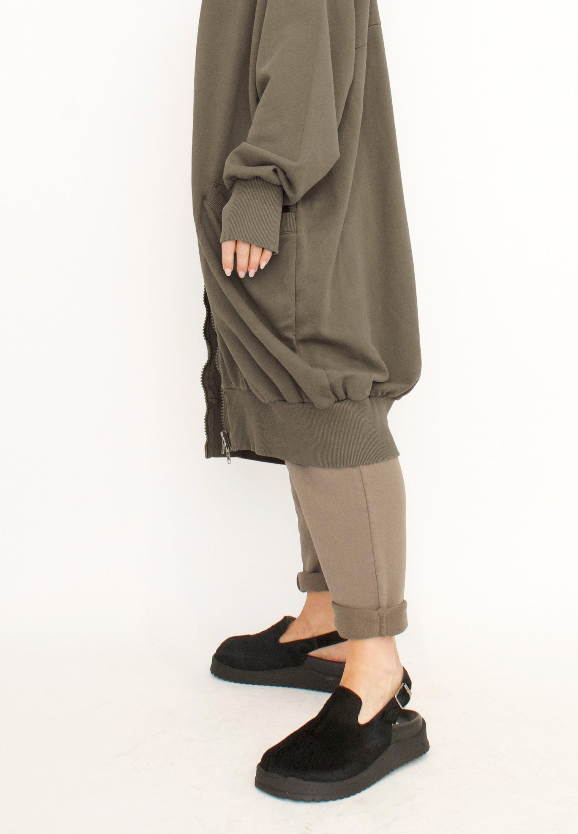Women's long zip up cardigan, with long sleeves, ribbed collar, cocoon shaped silhouette and pockets. Made in French Terry fabric by Sort Aarhus. Colour khaki. Side detail view.