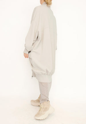 Women's long zip up cardigan, with long sleeves, ribbed collar, cocoon shaped silhouette and pockets. Made in French Terry fabric by Sort Aarhus. Colour creme. Side view.