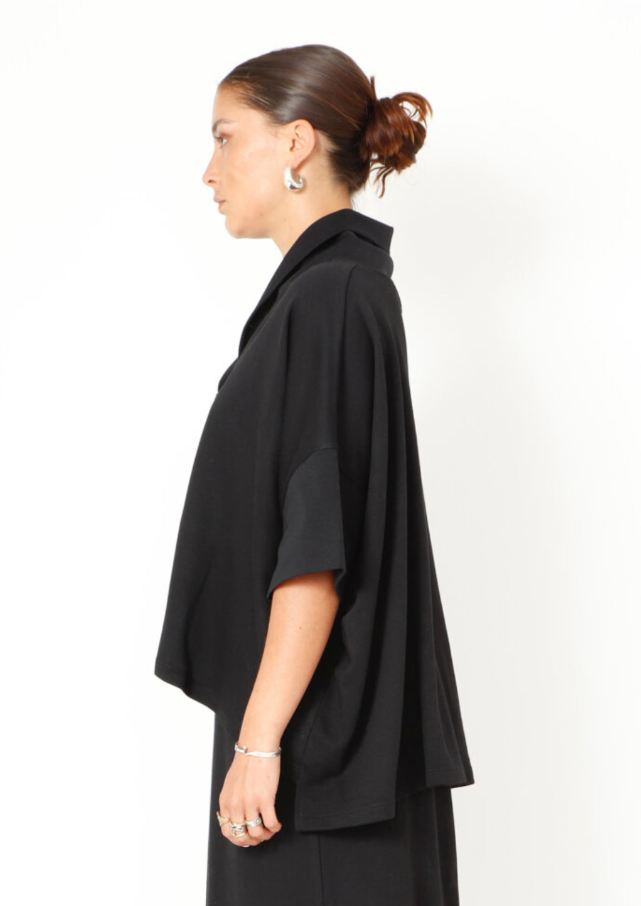 Women's boxy relaxed 1/2 sleeve blouse, with a wide, soft collar, made in a French Terry fabric. In colour black from Sort Aarhus. Side view.