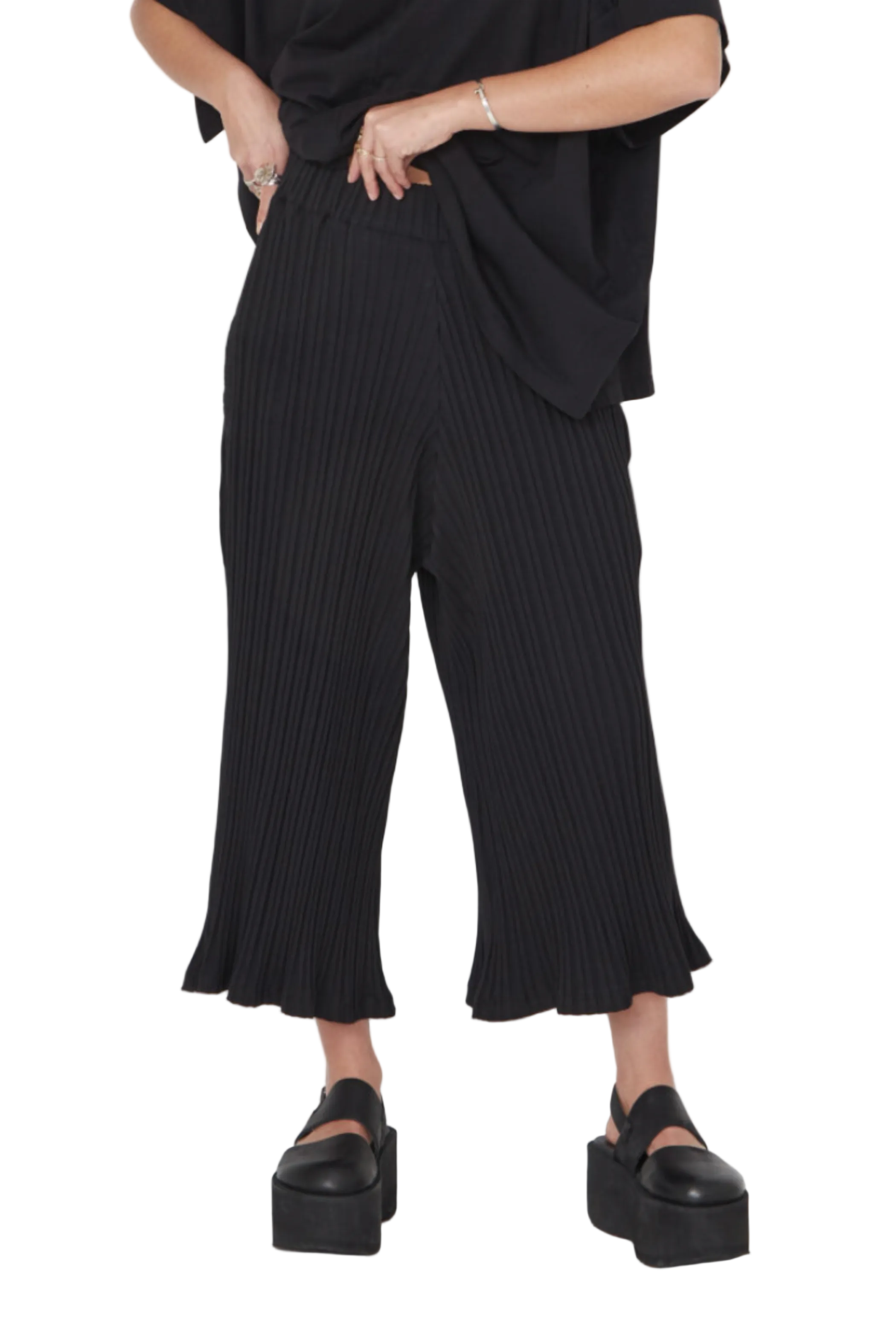 Women's cropped 3/4 length wide leg pant, with a wide elastic waistband, and pockets. Made in a stretchy rib textured organic cotton. Colour black by Sort Aarhus. Front view.